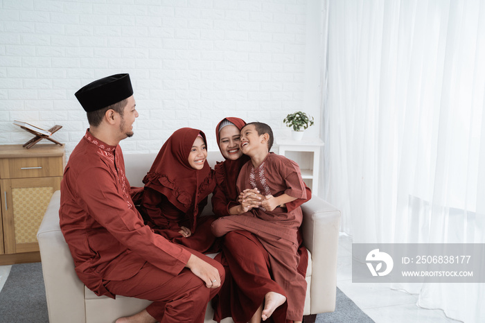 Malay Muslim family sitting on couch relax and joking enjoy holidays at home