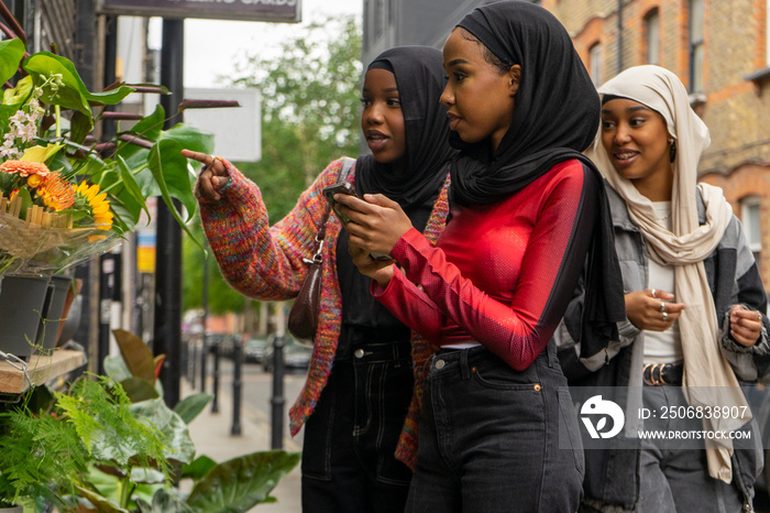 Young women wearing�hijabs�looking at flowers outside flower shop