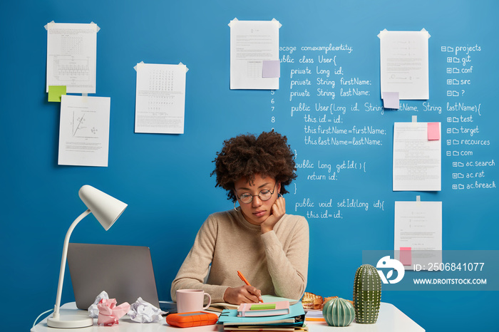 深色皮肤的女人计划工作日程，在记事本上做笔记，写下组织计划