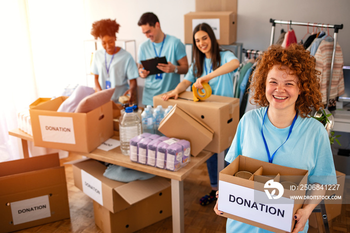 Woman and her colleague working in homeless shelter. Cheerful food drive manager. Happy diverse grou