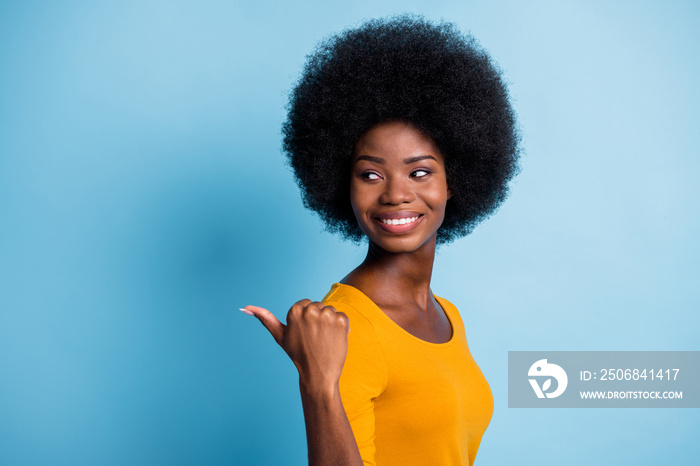 Photo portrait of curious black skinned girl pointing with finger looking at blank space smiling iso