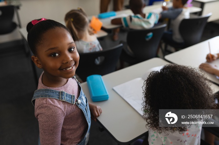 Smiling black schoolgirl standing and looking at camera in