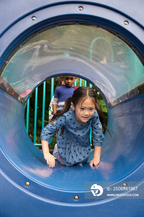 Girl crawling along playground tunnel