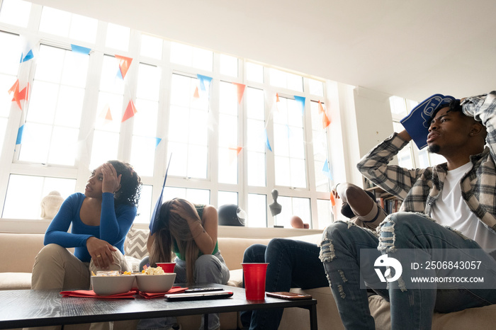 Friends watching sport game on�TV�at home