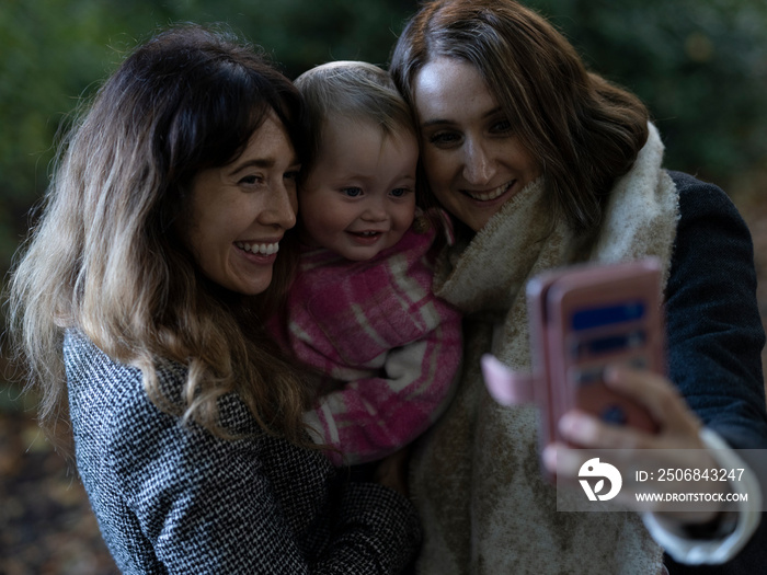 Women with baby taking selfie in park�