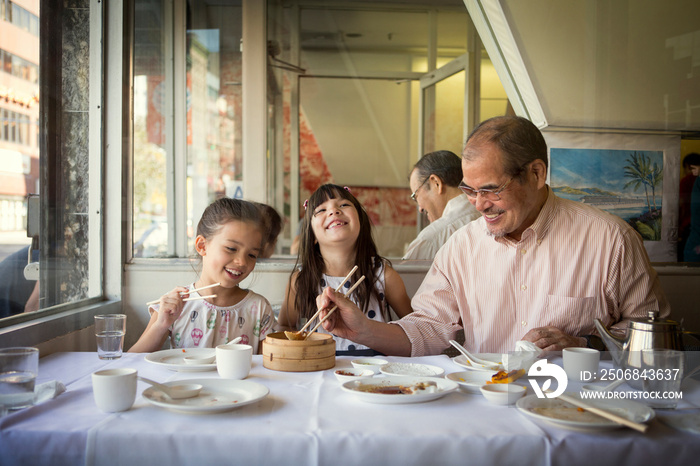 Grandfather and granddaughters having lunch in restaurant