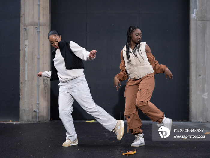 Two teenage girls dancing in city