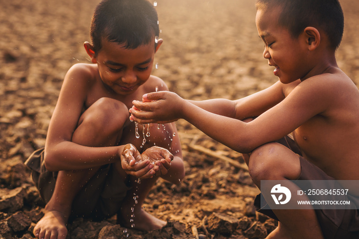 Asian local boys holding water with his hand at dry cracked land, Climate change, Environment conser