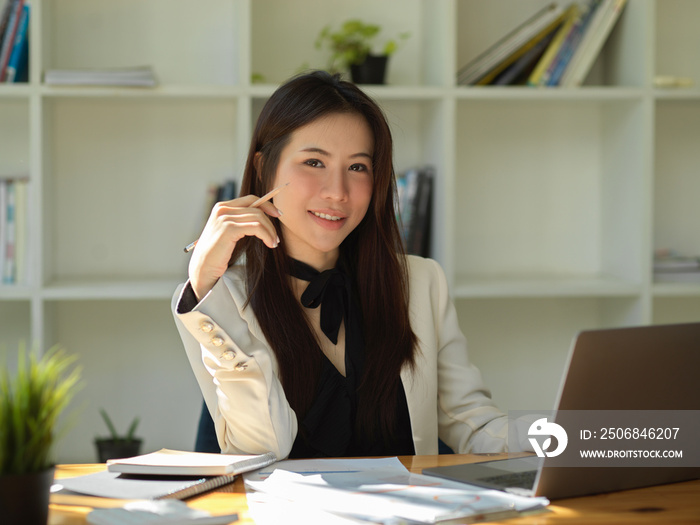 Attractive Asian young businesswoman sitting at her office desk