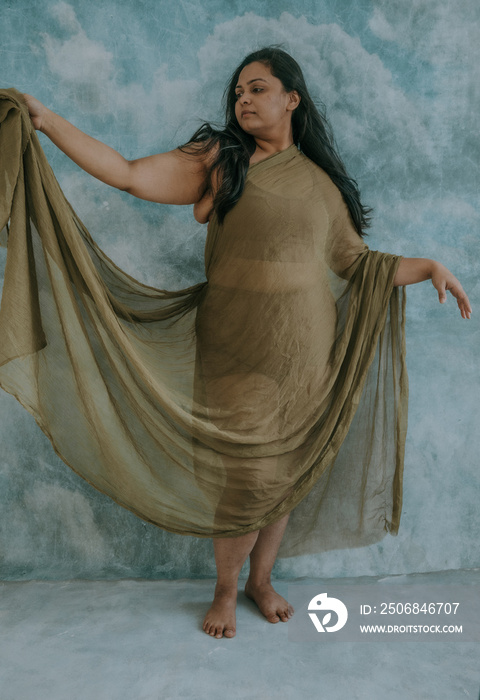 East Indian woman standing holding green fabric