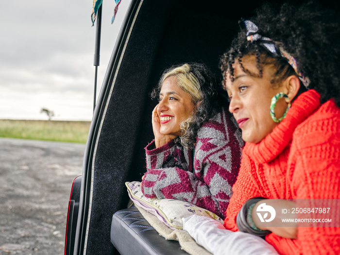 Women lying in back of van and looking at view