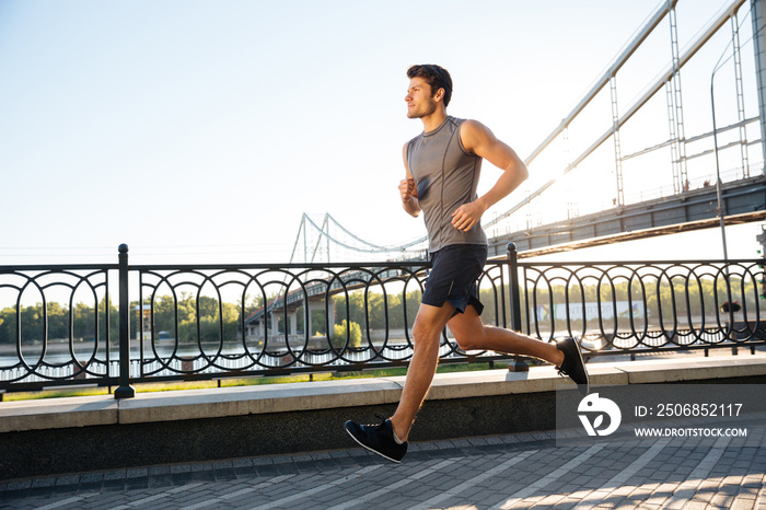 日落时分运动员沿着大桥奔跑的侧视图