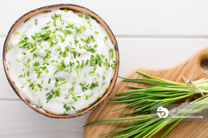 Bowl of cream cheese with green onions, dip sauce on wooden table.