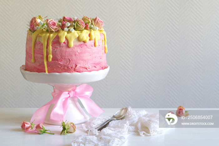 festliche rosa Erdbeer-Buttercreme-Torte mit gelb eingefärbtem Zuckerguss und mit Rosen und Schleier