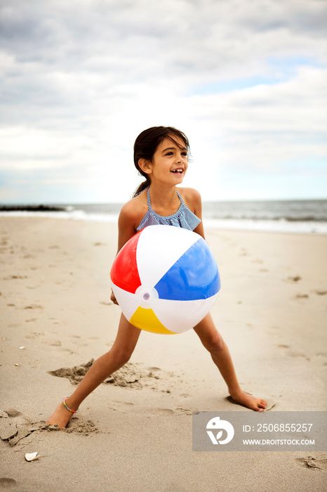 Little girl (6-7) playing with ball on beach