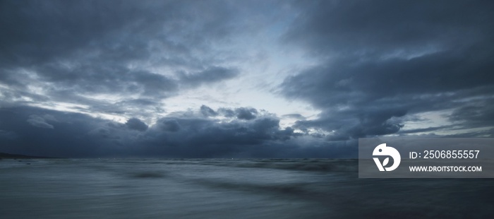 Dark storm sky above the Baltic sea, waves and water splashes. Dramatic cloudscape. Nature, environm