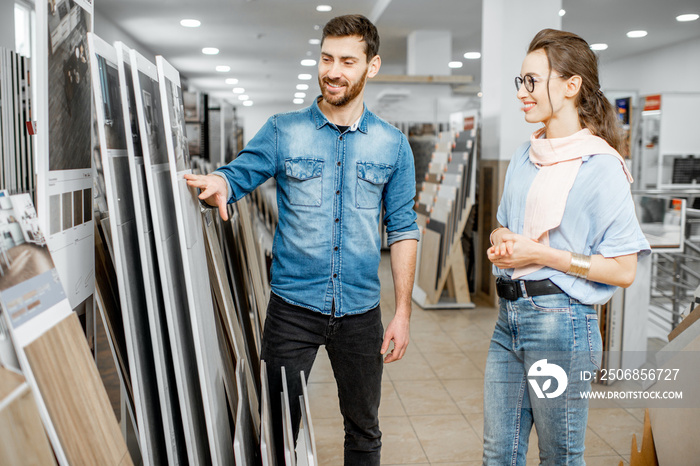 Beautiful young couple choosing ceramic tiles for their house repairment in the building shop