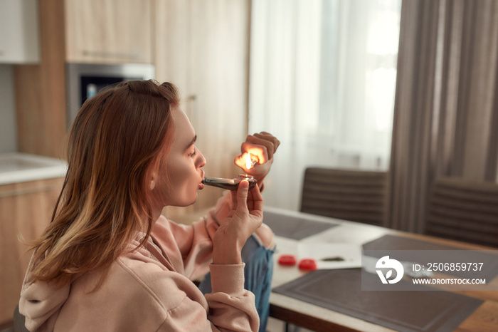 没有压力。一名年轻的高加索女子独自坐在金属管碗里点燃大麻