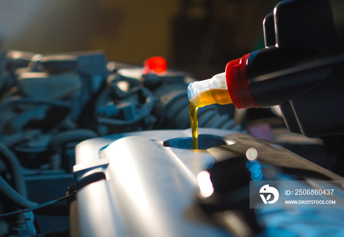 Engine oil change. Fresh engine oil pouring from the bottle into the automobile engine. Proper car c