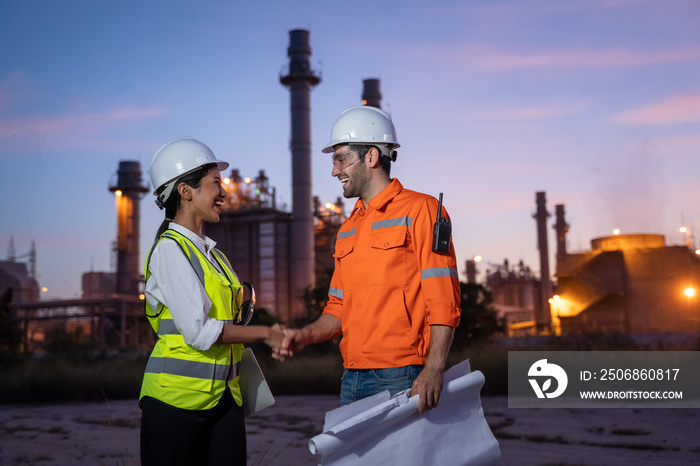 炼油厂行业工程师在炼油厂前进行团队合作时握手。