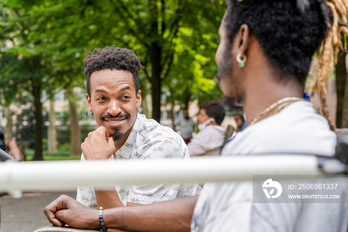 Two men talking on bench in park