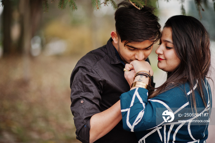 Love story of indian couple posed outdoor, man kiss her hand.