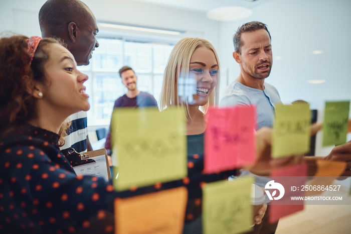 Smiling team of designers brainstorming together on an office wa