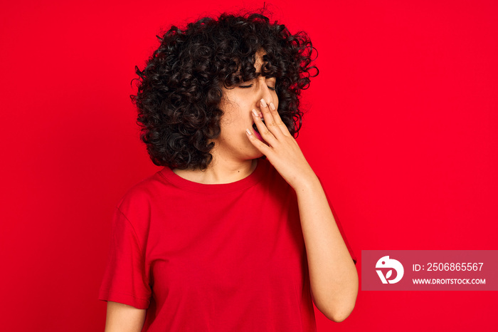 Young arab woman with curly hair wearing casual t-shirt over isolated red background bored yawning t