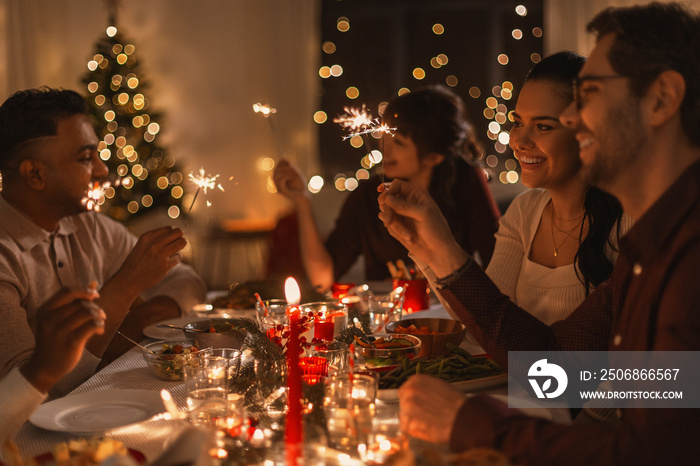 holidays and celebration concept - multiethnic group of happy friends with sparklers having christma