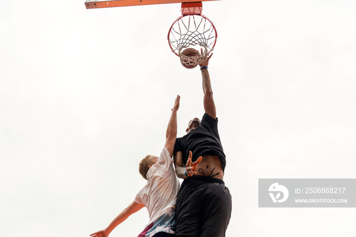 Low angle view of young men playing basketball