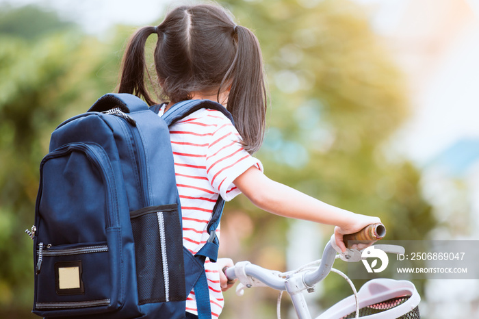 回到学校。可爱的亚洲小女孩背着背包骑自行车，去学校玩得很开心