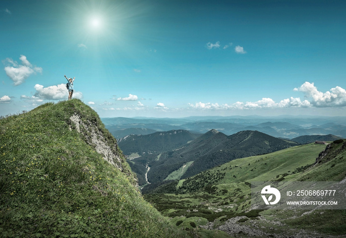 Woman hiking in mountains at sunny day time.