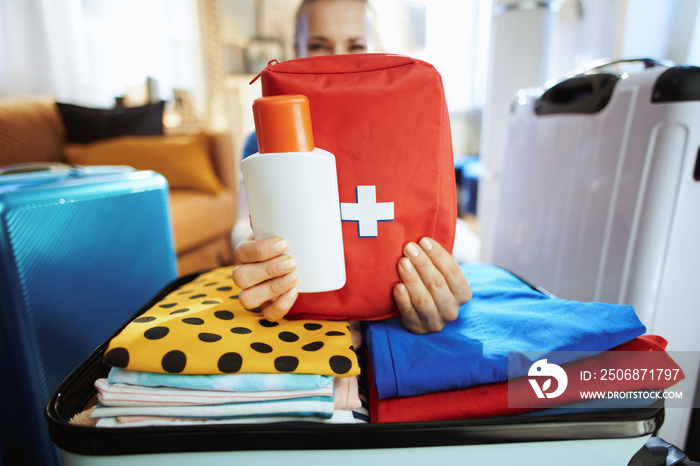 Closeup on traveller woman showing sunscreen and first aid kit