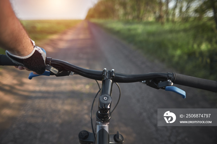 man riding a bike. holding bike handlebar with one hand in sport glove. summertime outdoor leisure s