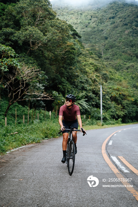 A young female cyclist riding her gravel bike in the mountains.