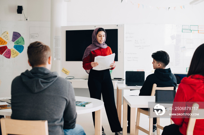 Confident teenage girl giving presentation in class at university