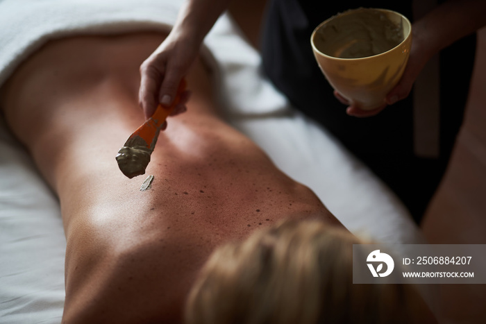 Close up therapist applying healthy spa mud