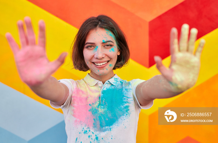 Happy woman with colorful face and clothes showing hands