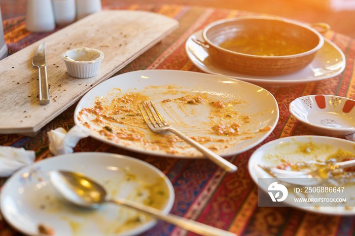 桌子上有一块明亮的桌布，阳光明媚，用勺子和叉子清空脏盘子