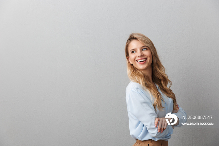 Photo of charming blond businesswoman with long curly hair smiling and standing with hands crossed n