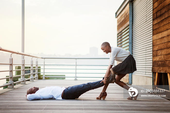 Side view of couple playing on wooden pier