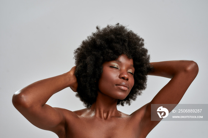 Portrait of sensual african american female model with afro hair and perfect glowing skin posing wit