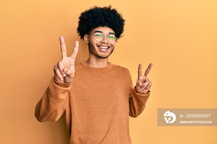 Young african american man with afro hair wearing casual winter sweater smiling looking to the camer