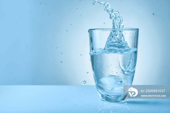 Glass of fresh water with splash on color background