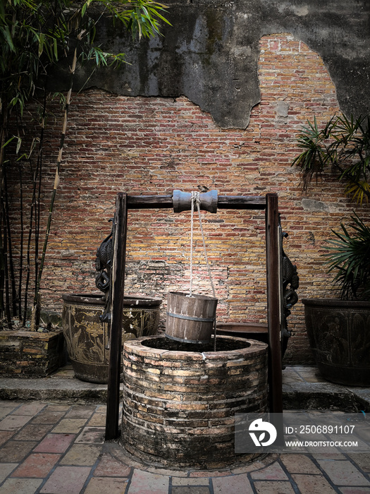 Ancient artesian well  with hanging wood bucket and wooden roof.