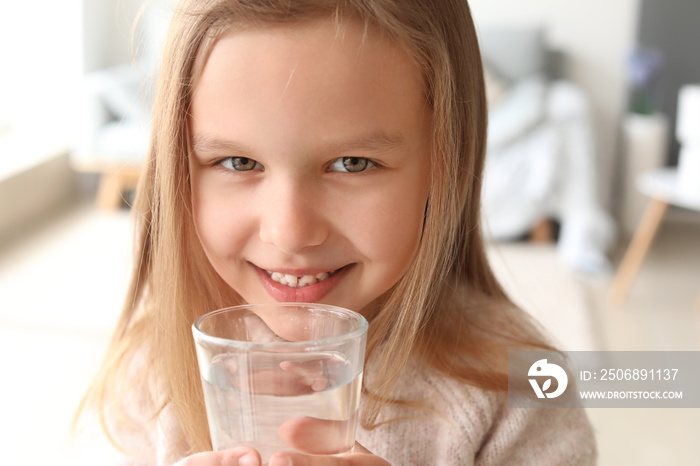 Cute little girl drinking water at home