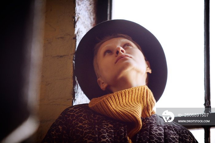 Young woman wearing hat looking up