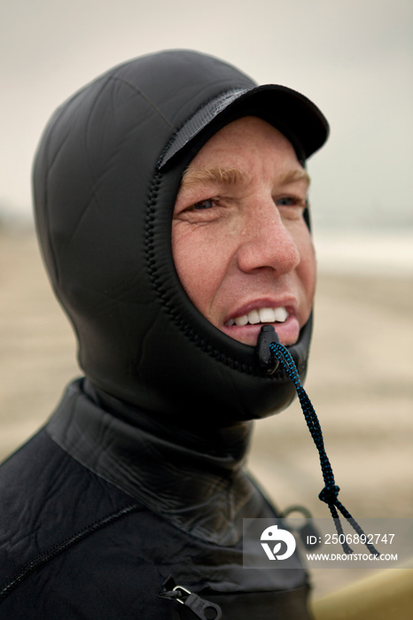 Portrait of man wearing wetsuit on sandy beach