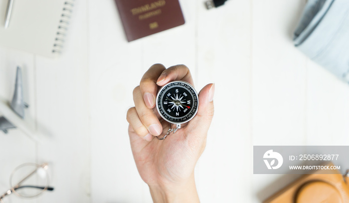 Explorer holding compass surrounded by travel accessories