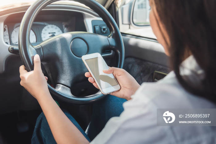 Young woman using smart phone while driving a car